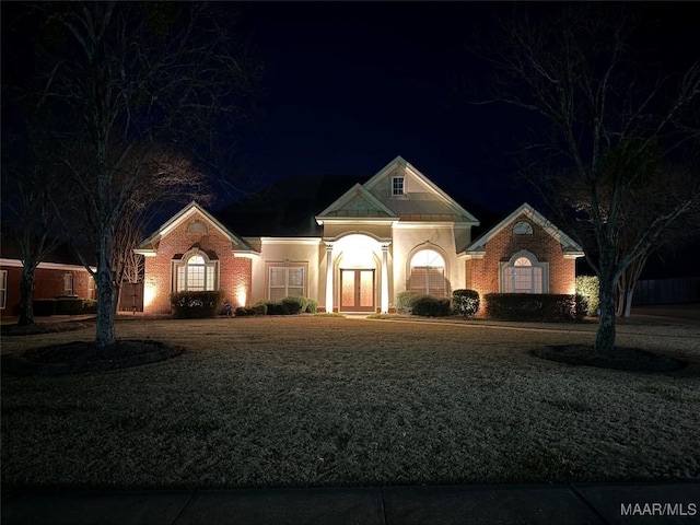 view of front of property with a lawn, brick siding, and french doors