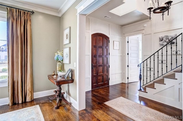 entrance foyer featuring visible vents, crown molding, baseboards, stairway, and wood finished floors