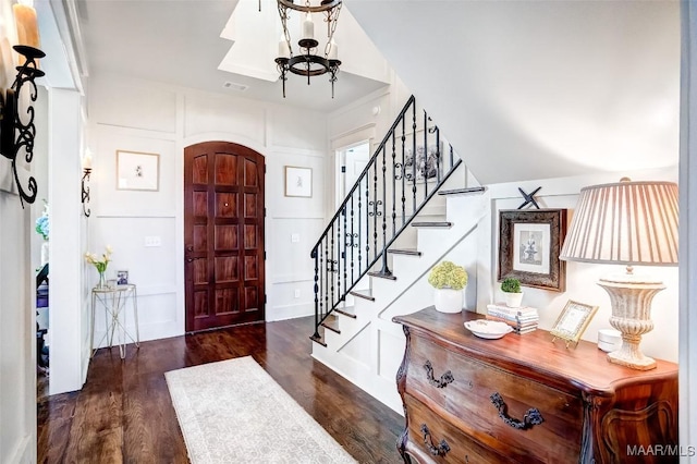 entryway with visible vents, wood finished floors, stairway, an inviting chandelier, and a decorative wall