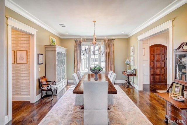 dining room with visible vents, baseboards, dark wood finished floors, ornamental molding, and a notable chandelier