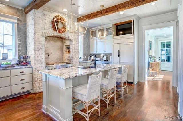 kitchen featuring paneled fridge, beam ceiling, dark wood-type flooring, a sink, and a chandelier