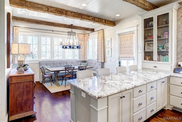 kitchen featuring light stone countertops, beam ceiling, a peninsula, dark wood-type flooring, and white cabinets