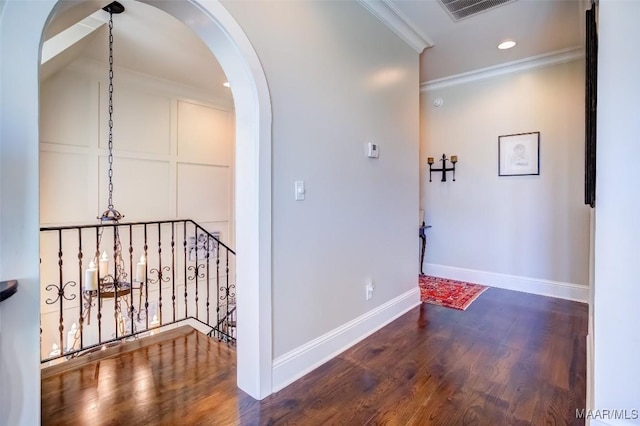 corridor with visible vents, baseboards, ornamental molding, wood finished floors, and arched walkways