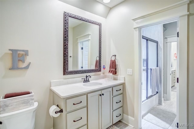 full bathroom featuring baseboards, bath / shower combo with glass door, toilet, and vanity