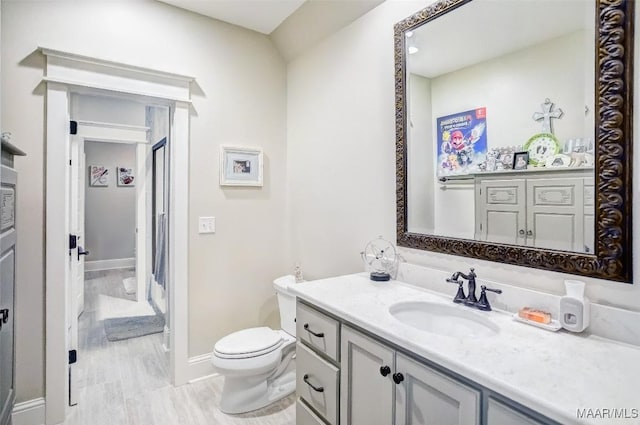 bathroom featuring toilet, vanity, and baseboards