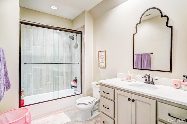 bathroom with combined bath / shower with glass door, toilet, and vanity