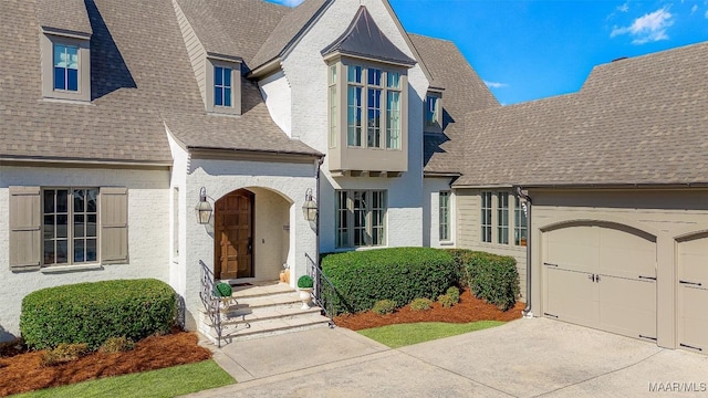 view of front of property featuring roof with shingles, concrete driveway, and an attached garage