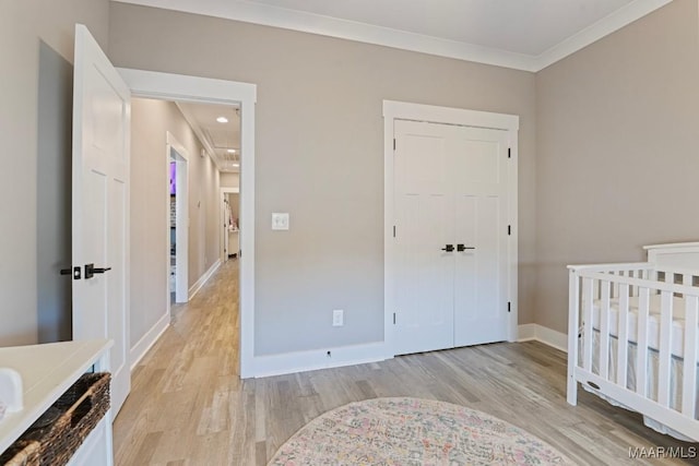 bedroom with a closet, baseboards, crown molding, and light wood-style floors