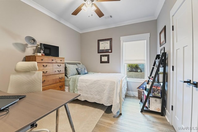 bedroom featuring light wood finished floors, visible vents, crown molding, baseboards, and ceiling fan