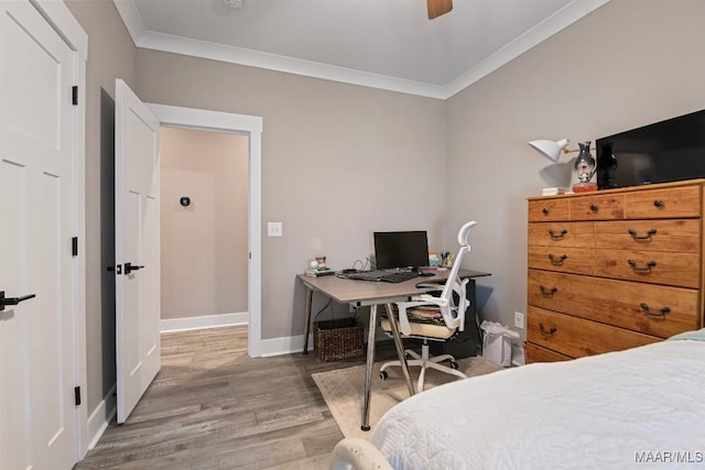 bedroom with a ceiling fan, crown molding, baseboards, and wood finished floors