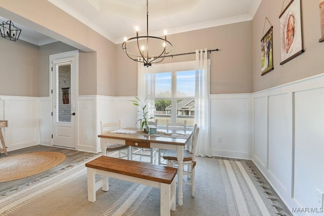 dining room featuring wood finished floors, a wainscoted wall, a raised ceiling, and a chandelier