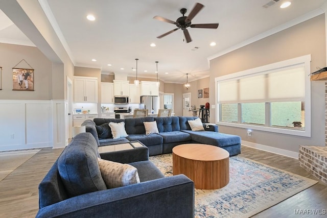 living room with crown molding, a decorative wall, recessed lighting, and light wood-style floors