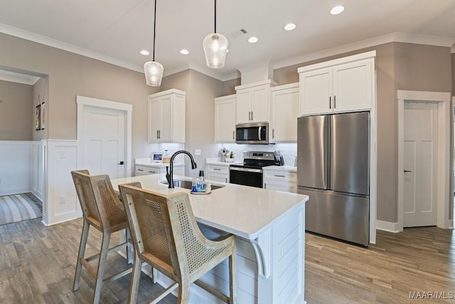 kitchen featuring a sink, stainless steel appliances, ornamental molding, and light countertops