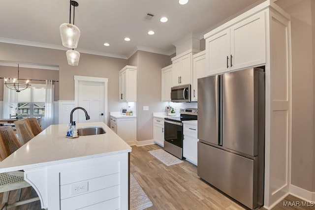 kitchen featuring ornamental molding, a sink, white cabinetry, stainless steel appliances, and light wood-style floors