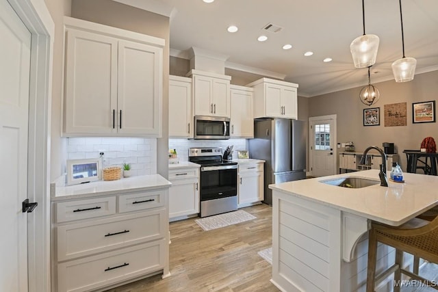 kitchen featuring visible vents, ornamental molding, a sink, backsplash, and appliances with stainless steel finishes