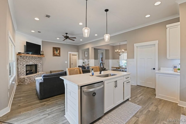 kitchen featuring a brick fireplace, dishwasher, white cabinets, and a sink