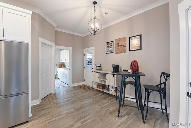 office featuring light wood finished floors, visible vents, crown molding, baseboards, and an inviting chandelier