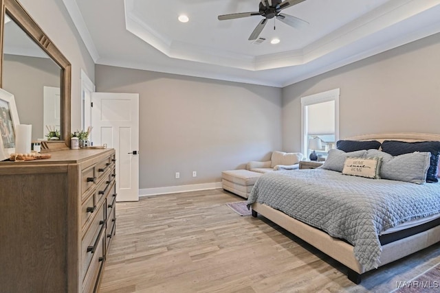 bedroom featuring visible vents, a tray ceiling, crown molding, light wood finished floors, and baseboards