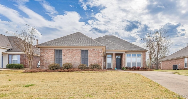 view of front of home featuring a front lawn, central air condition unit, and brick siding