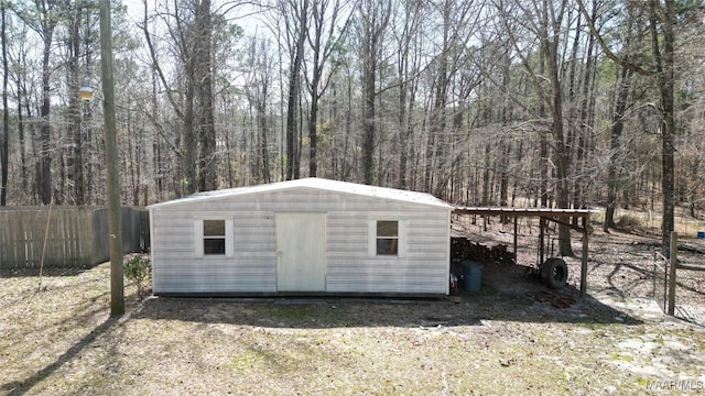 view of shed featuring a wooded view and fence