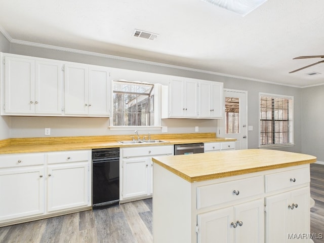 kitchen with a sink, dishwasher, light wood-style flooring, and crown molding