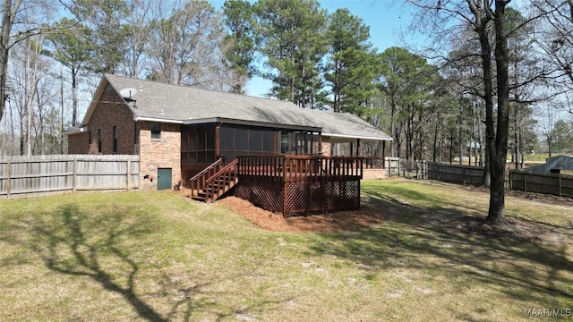 back of property featuring a yard, a fenced backyard, a sunroom, a shingled roof, and brick siding