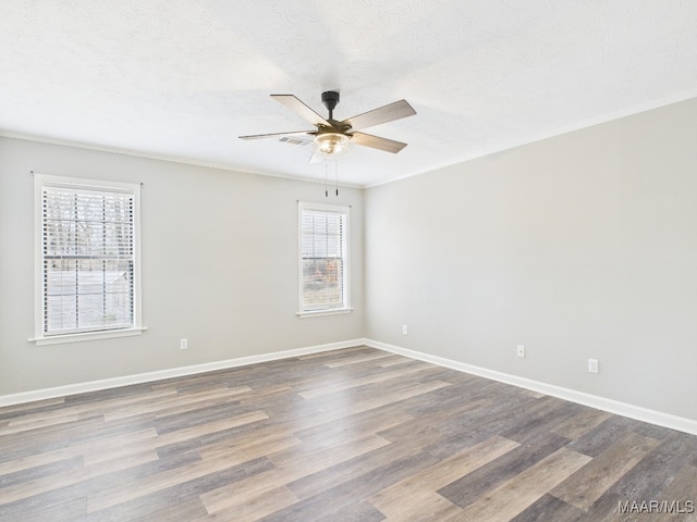 spare room with wood finished floors, baseboards, and a textured ceiling