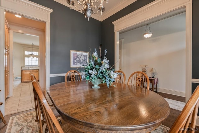 dining area featuring light tile patterned floors, baseboards, crown molding, and an inviting chandelier