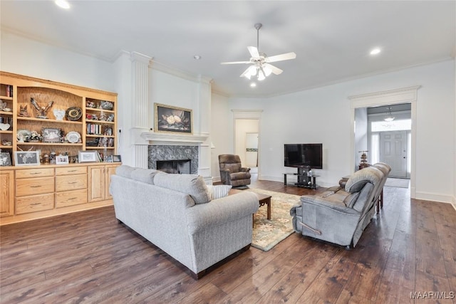 living room featuring a premium fireplace, dark wood-style floors, a ceiling fan, and ornamental molding