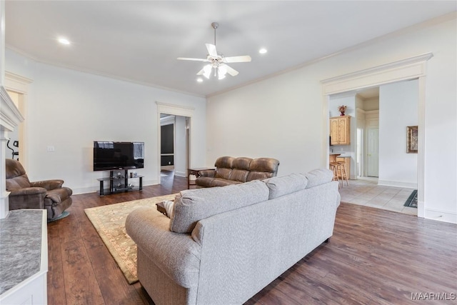 living area featuring a ceiling fan, crown molding, wood finished floors, and baseboards