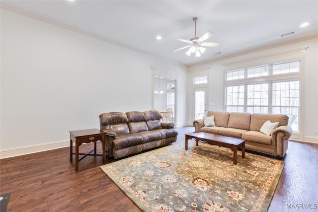 living area featuring visible vents, crown molding, baseboards, dark wood finished floors, and a ceiling fan