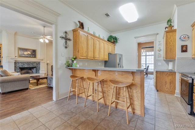 kitchen featuring light tile patterned floors, a breakfast bar area, a fireplace, and stainless steel appliances