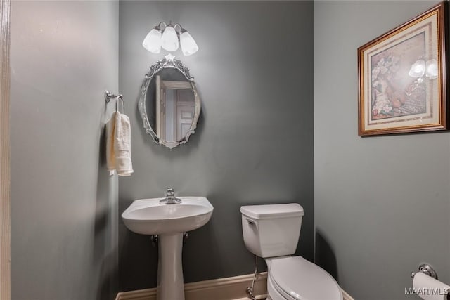 half bathroom with baseboards and toilet