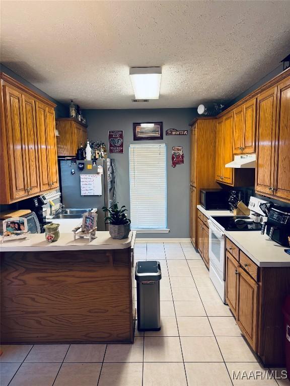 kitchen with light tile patterned floors, freestanding refrigerator, under cabinet range hood, black microwave, and white electric range