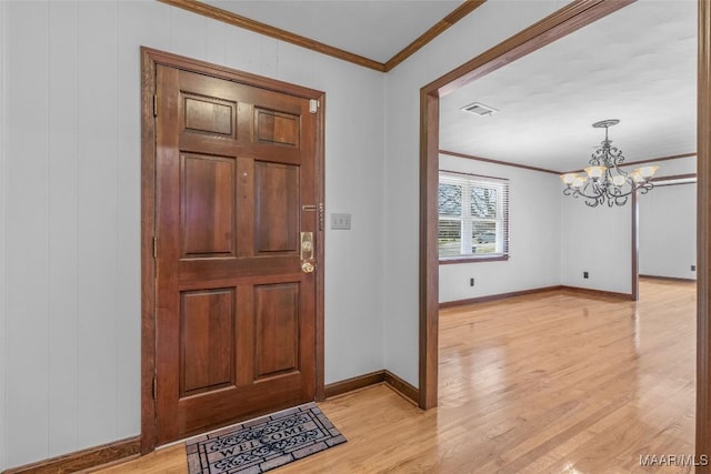 foyer entrance with light wood finished floors, visible vents, baseboards, a chandelier, and ornamental molding