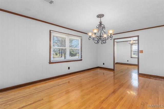 empty room with a wealth of natural light, crown molding, light wood-type flooring, and baseboards