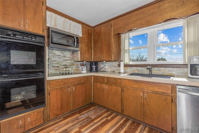 kitchen with black appliances, a sink, tasteful backsplash, light countertops, and dark wood-style flooring