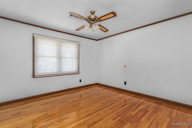 empty room featuring crown molding, light wood-style flooring, baseboards, and ceiling fan