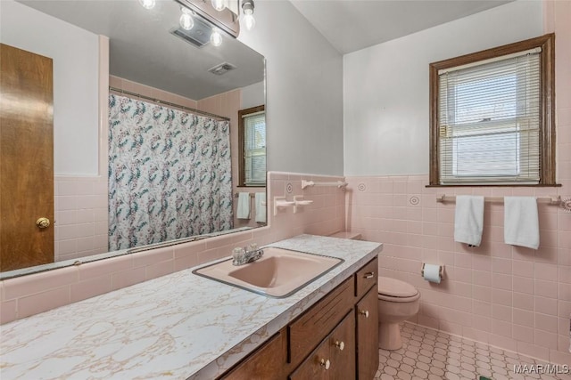 bathroom featuring visible vents, plenty of natural light, tile walls, and toilet