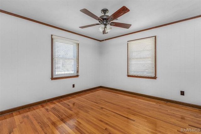 empty room with baseboards, ceiling fan, crown molding, and hardwood / wood-style flooring