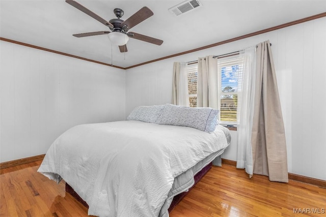 bedroom with visible vents, crown molding, baseboards, ceiling fan, and wood finished floors