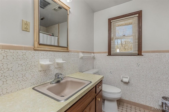 bathroom featuring visible vents, toilet, a shower with shower curtain, wainscoting, and vanity