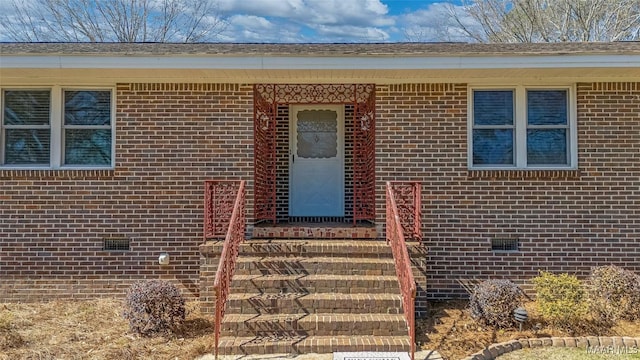 doorway to property featuring crawl space and brick siding