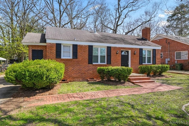 view of front of house with brick siding, a chimney, and a front lawn