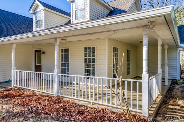 entrance to property featuring a porch and a shingled roof