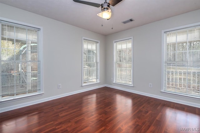 empty room with a ceiling fan, visible vents, wood finished floors, and baseboards