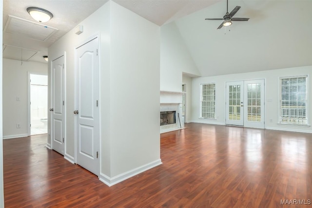 unfurnished living room with wood finished floors, baseboards, attic access, a high end fireplace, and ceiling fan