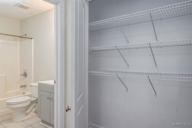 interior space featuring tile patterned flooring, visible vents, toilet, vanity, and  shower combination