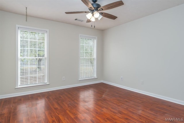 empty room with visible vents, baseboards, ceiling fan, and dark wood-style flooring