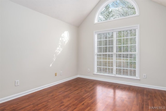 spare room with vaulted ceiling, baseboards, and wood finished floors